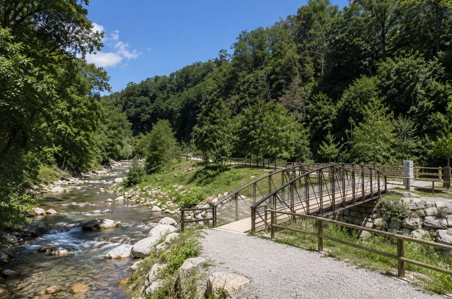 Il fiume Cassarate con un ponte pedonale e un sentiero nel bosco